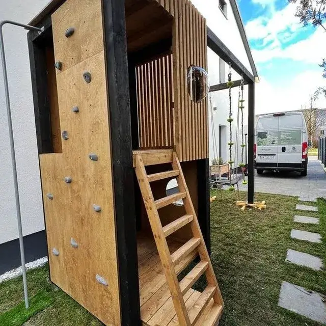 Kućica za decu od punog drveta za dvorište sa crnom konstrukcijom sa raznim preprekama za penjanje.