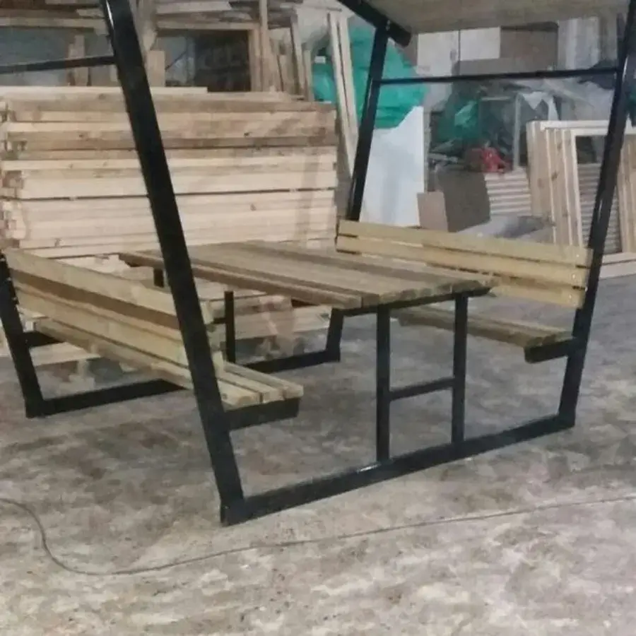 Mini letnjikovac drvo-metal sa stočićem u sredini i drvenim krovom.