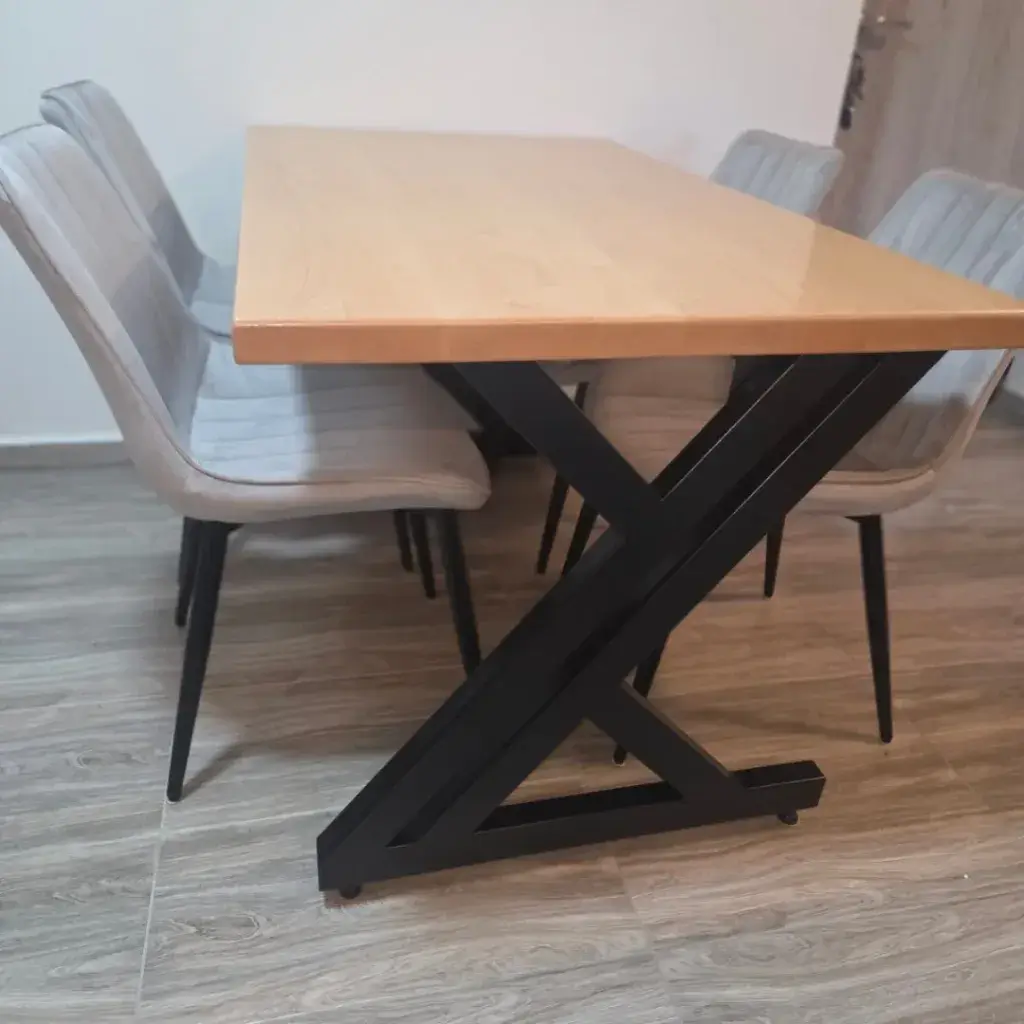 Trpezarijski sto sa masivnom drvenom pločom i crnim metalnim nogarima u obliku slova z i četiri sive stolice.